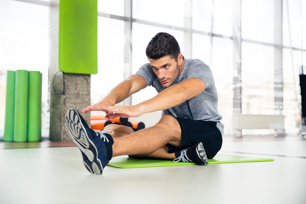 Portrait-of-a-fitness-man-doing-stretching-exercises-at-gym
