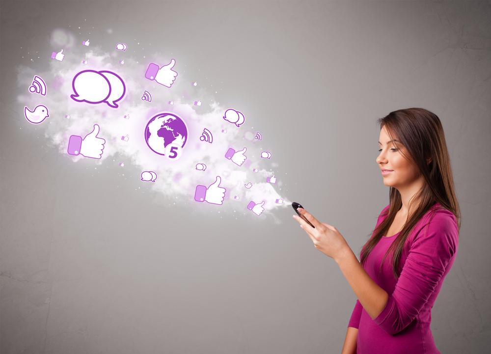 Pretty-young-girl-holding-a-phone-with-social-media-icons-in-abstract-cloud