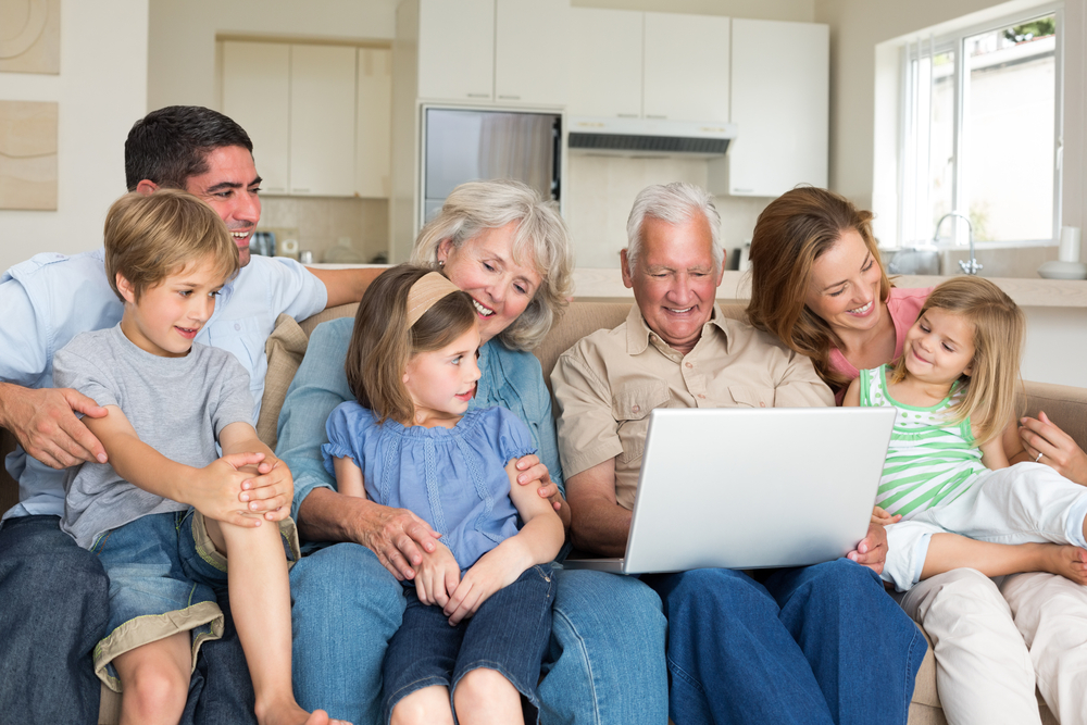 Smiling-multigeneration-family-using-laptop-in-living-room